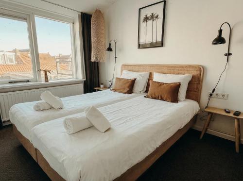 a bedroom with a large bed with white sheets and pillows at Multi-bedroom stay 9 Rooms near Beach in Zoutelande