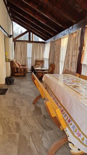 a dining room with a table and chairs and a room with windows at Cabana Angela in Râșca