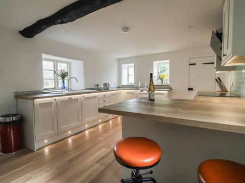 a kitchen with white cabinets and a counter with a stool at Manor Cottage in Ilminster
