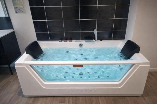 a bath tub filled with blue water in a bathroom at Suite Cinéma #7#- Jacuzzi in Roubaix