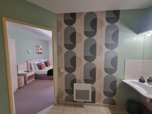 a bathroom with a sink and a bedroom with a bed at Hôtel Le Kolibri in Tournus