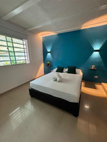 a bedroom with a bed with a blue wall at Hotel Rodadero Relax in Gaira