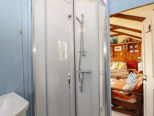 a bathroom with a shower and a bed in a room at The Cabin in Cawsand