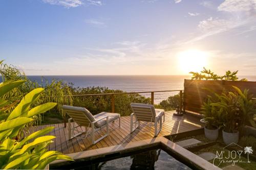 a deck with two chairs and the ocean in the background at VILLA ESCALE TROPICALE - classée 5 in Petite Île