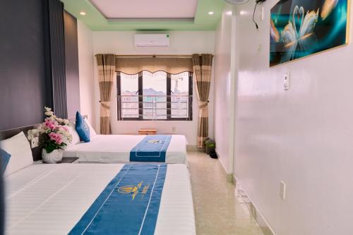 two beds in a room with a window at Cat Ba Bay Vision Hotel in Cat Ba