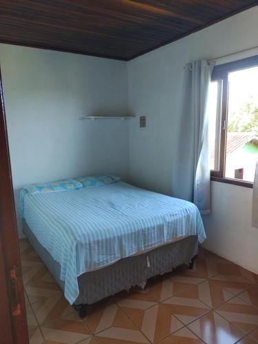ein Schlafzimmer mit einem Bett in einem Zimmer mit Fenster in der Unterkunft Refúgio Madá in Florianópolis