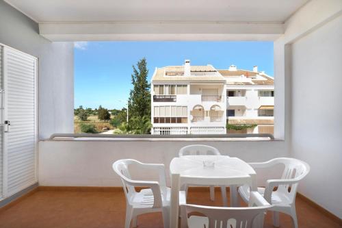 a white table and chairs in a room with a large window at Golden Club Cabanas in Cabanas de Tavira