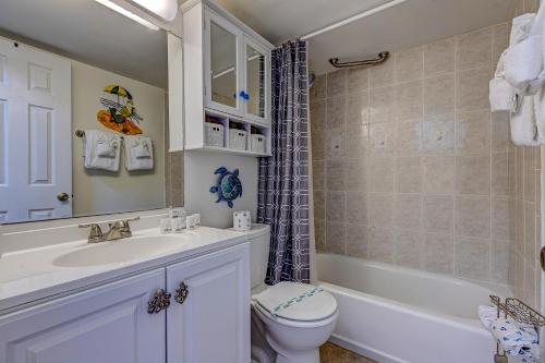 a bathroom with a toilet and a tub and a sink at The Ocean Calls Harbour Beach 612 in Daytona Beach