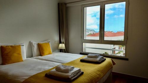 a bedroom with two towels on a bed with a window at FLH Funchal Modern Apartment with Pool in Funchal