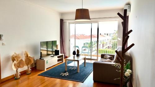a living room with a couch and a tv at FLH Funchal Modern Apartment with Pool in Funchal
