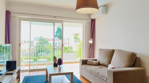 a living room with a couch and a large window at FLH Funchal Modern Apartment with Pool in Funchal
