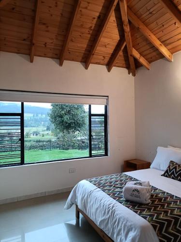 a bedroom with a bed and a large window at Casa Campestre Arama in Paipa