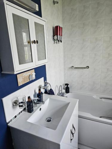 a bathroom with a white sink and a bath tub at Notre Petit Chateau in Rosslare Harbour