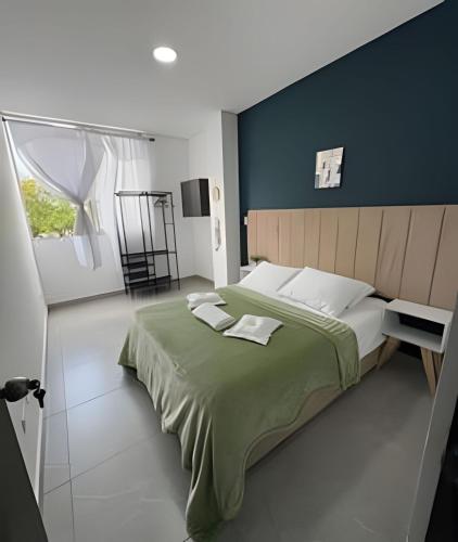 a bedroom with a large bed with a green blanket at alojamientos la martina in Cali