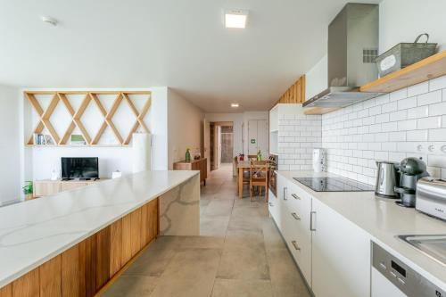 a kitchen with white counter tops and wooden cabinets at Casas do Forneiro - T2 in Nordeste