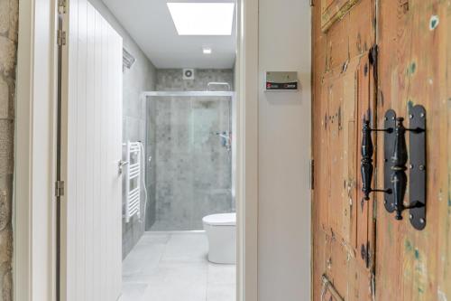 a bathroom with a toilet and a wooden door at Casas do Forneiro - T2 in Nordeste