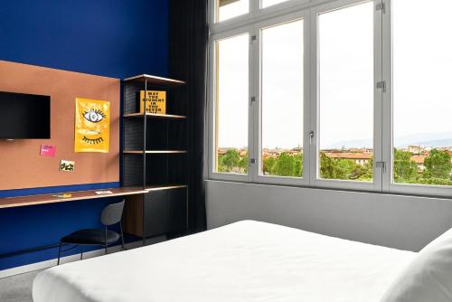 a bedroom with a bed and a desk and windows at The Social Hub Florence Lavagnini in Florence