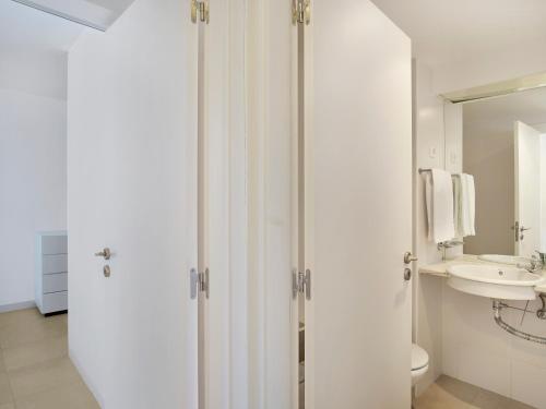 a white bathroom with a toilet and a sink at Golden Club Cabanas in Cabanas de Tavira