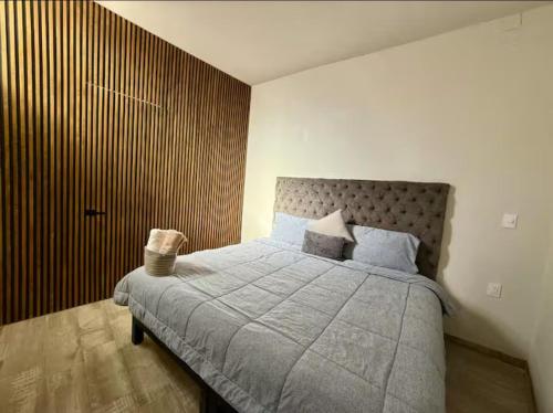 a bedroom with a bed and a wooden wall at Canteira Boutique Aparthotel in Guanajuato