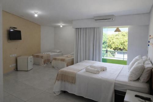 a hotel room with two beds and a window at Pousada Solar Dos Carneiros in Praia dos Carneiros