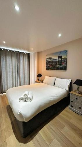 a bedroom with a large bed with two slippers on it at Britannia Apartments in Edinburgh