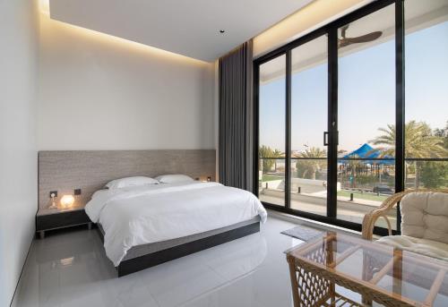 a bedroom with a bed and a large window at شاليهات وفلل سُبات in Half Moon Bay
