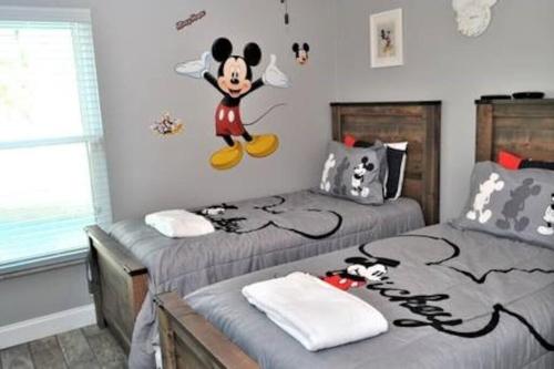a bedroom with two beds with mickey mouse on the wall at Luxury Retreat with 2 Master Suites Pool & Hot Tub BBQ Pool Table 2 Miles Disney in Orlando