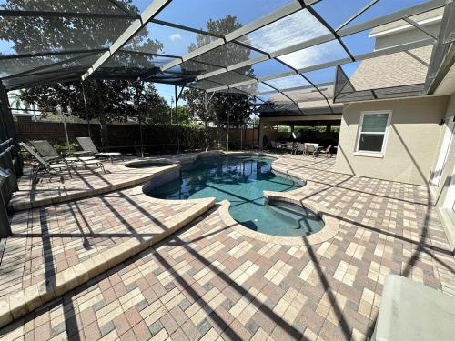 a patio with a swimming pool with an umbrella at Luxurious Getaway Pool Hot Tub Theater Gym Outdoor Kitchen BBQ 2 Miles to Disney in Orlando