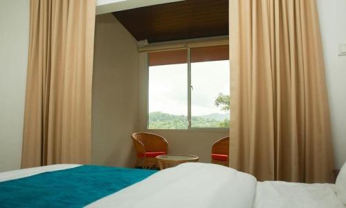 a bedroom with a bed and a window and chairs at The Villa Rochelle Kandy in Kandy
