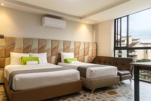 a hotel room with two beds and a couch at Hotel AirPort Pereira in Pereira
