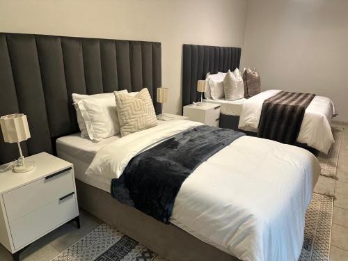 a bedroom with two beds with white sheets at Phela Guesthouse in Edenvale
