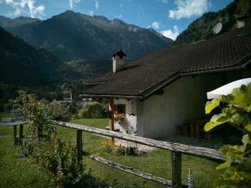 a small house with a fence and mountains in the background at Casa Davide Valdaone in Daone