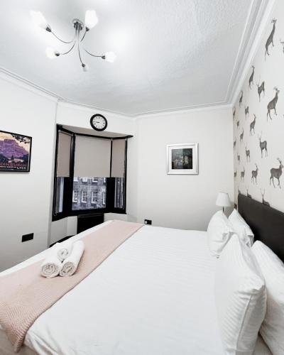 a bedroom with a large white bed with two slippers at Old Town Castle Apartment in Edinburgh