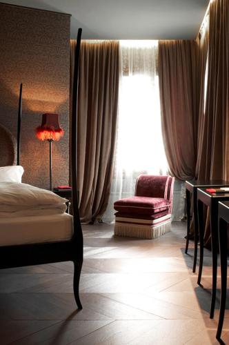 a bedroom with a bed and a chair and a window at Hotel Palazzo Barbarigo Sul Canal Grande in Venice