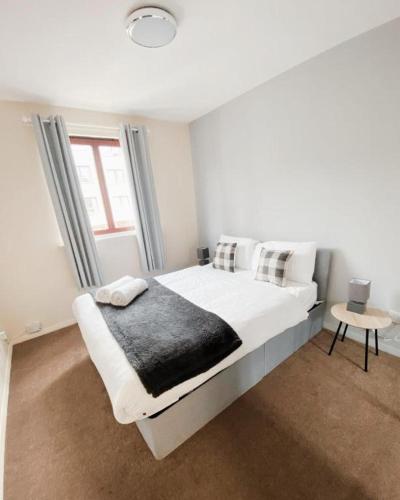a white bedroom with a large white bed and a window at The Easter Suites with free parking in Edinburgh