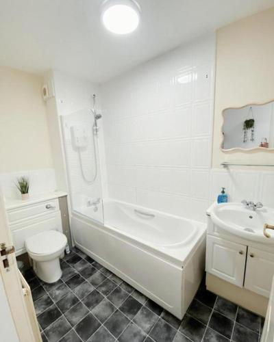 a white bathroom with a tub and a toilet and a sink at The Easter Suites with free parking in Edinburgh