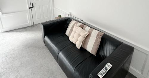 a black leather couch with two pillows on it at New Town Residence in Edinburgh