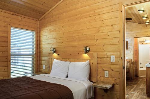 a bedroom with a bed and a wooden wall at Yosemite Lakes Cabin & Cottages in Harden Flat