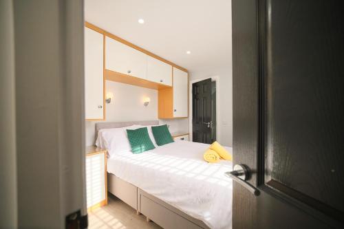 a bedroom with a large white bed with green pillows at 1 Bedroom Lodge By Travel Lets Self Catering Accommodation Rathmullen With Hot Tub in Ramelton