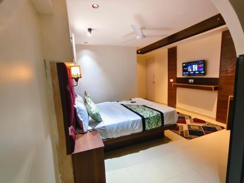a bedroom with a bed and a tv on a wall at Hotel Gandharva Executive in Pune