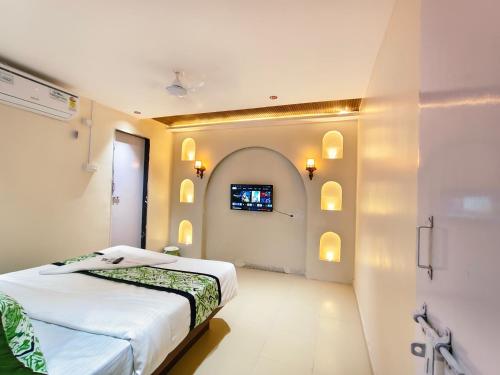 a bedroom with a bed and a tv on the wall at Hotel Gandharva Executive in Pune