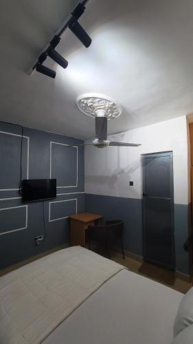 a bedroom with a bed and a desk and a ceiling fan at Exodus Hotel & Restaurant in Aiyetoro