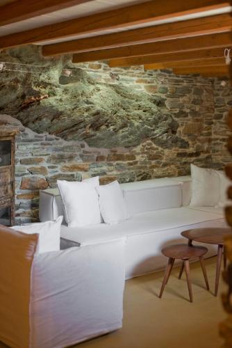 a white couch in a room with a stone wall at Stone Wave Kythnos in Loutra