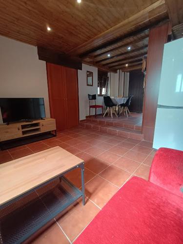 a living room with a tv and a red couch at La casa de Somiedo in Pola de Somiedo
