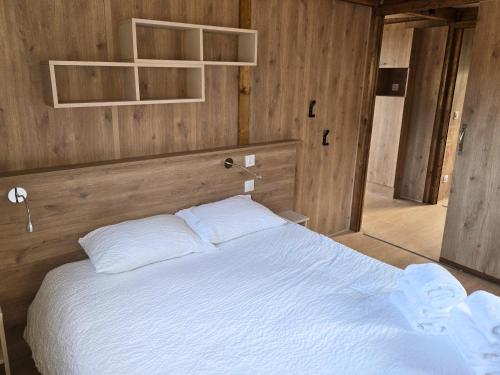 a bedroom with a large white bed with wooden walls at Tiny d'Monts in Brullioles