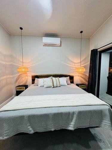 a bedroom with a large white bed with two lights at Stillness Suite - Tamarindo - Pinilla - Avellanas - Pool - BBQ in San José Pinilla