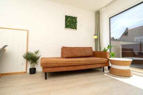 a brown couch in a living room with a window at Sali Homes Apartmenthaus Schlossgasse in Neckarsulm