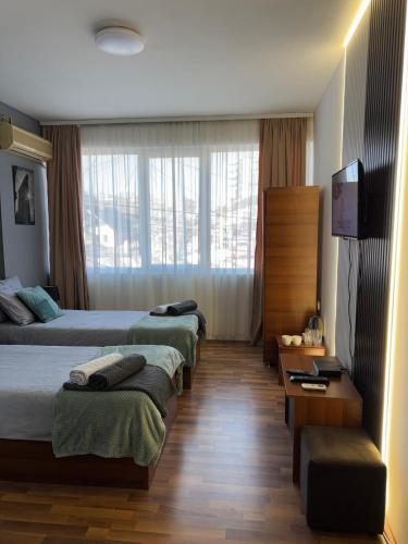 a hotel room with four beds and a flat screen tv at Zulu Apartments and Studios in Kumanovo