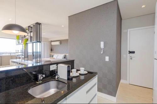 a bathroom with a sink and a bedroom at Apartamento Premium - Melhor vista de Curitiba in Curitiba