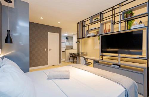 a bedroom with a large white bed and a flat screen tv at Apartamento Premium - Melhor vista de Curitiba in Curitiba